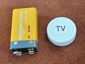 Flic button with 9-volt battery to show scale